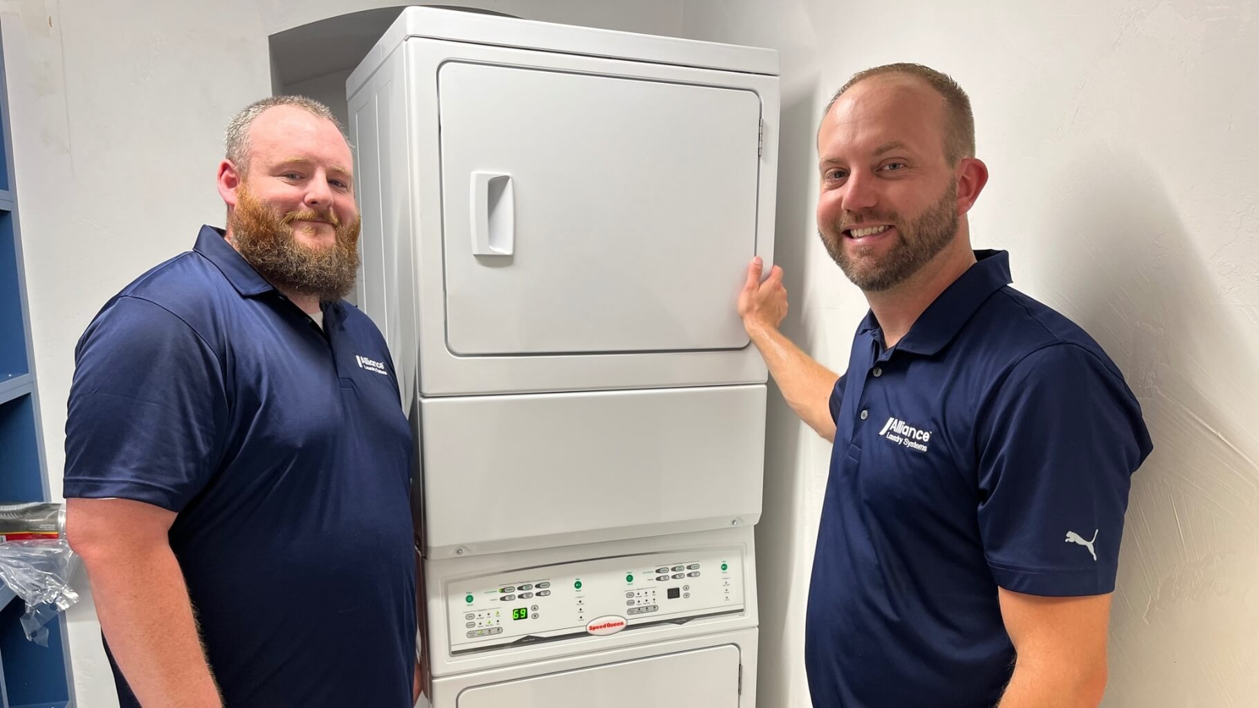 Two employees posing with stacked washer dryer