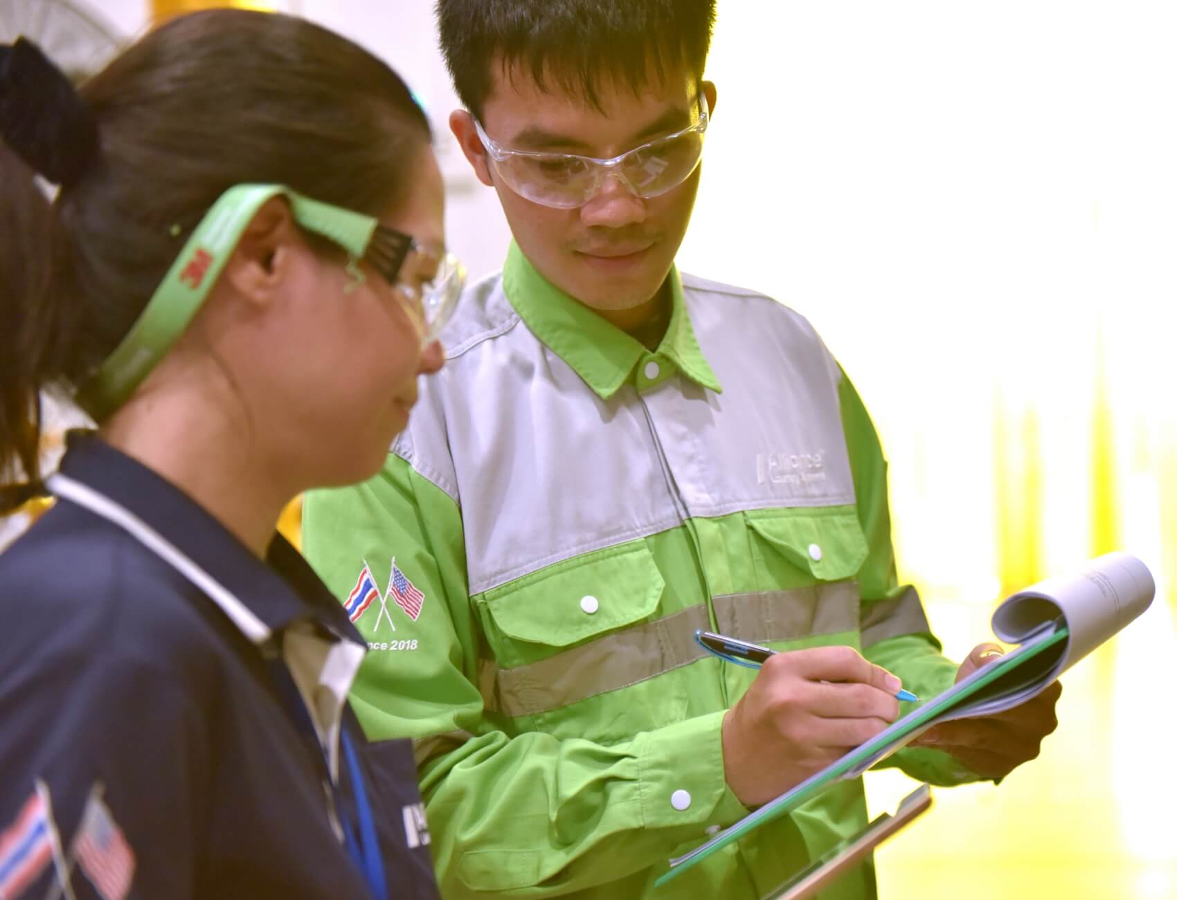 Thai employees in safety gear going over paperwork