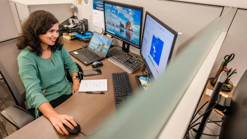 Corporate employee working on desktop monitors in cubicle at Ripon office