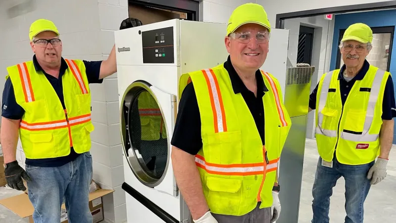 Three Alliance employees during installation of gifted laundry equipment