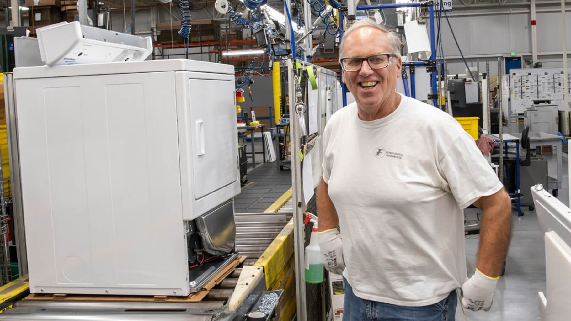Smiling employee in front of machine in the factory