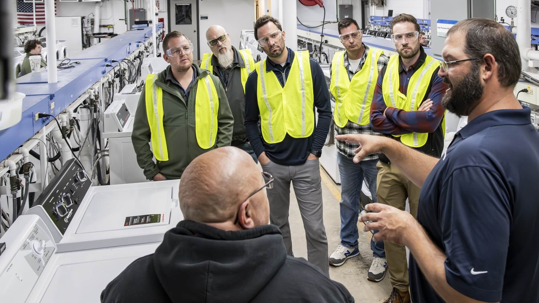 Group of men in safety gear listen to training in Engineering Lab