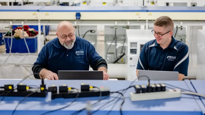 Two Alliance employees working on laptops in engineering facility
