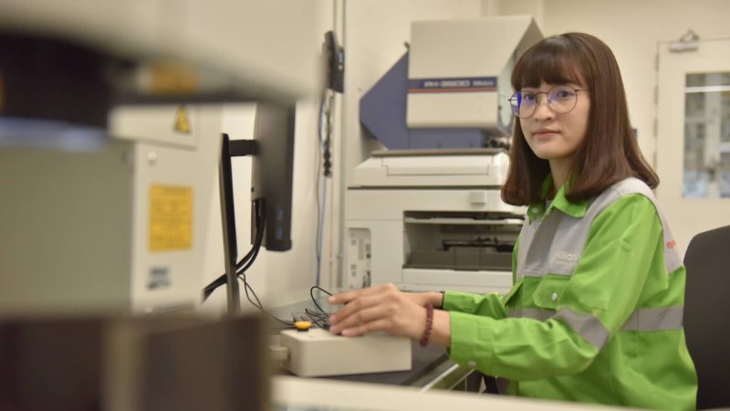 alliance employee in green jacket working in manufacturing facility